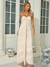 Woman in a strapless beige gown standing in a decorated room with disco balls.